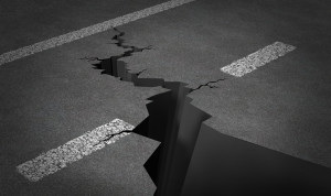 Failed strategy and journey problems with an asphalt highway with painted lines and broken by a huge crack splitting the road into two parts as business or life concept of road blocks and challenging obstacles to a planned path.